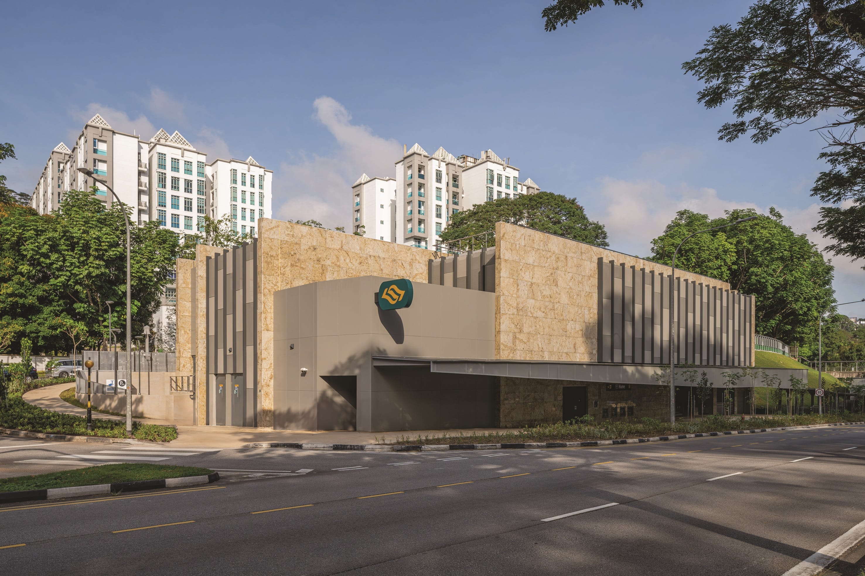 Exterior view of an office building with a golden leaf logo under a blue sky.